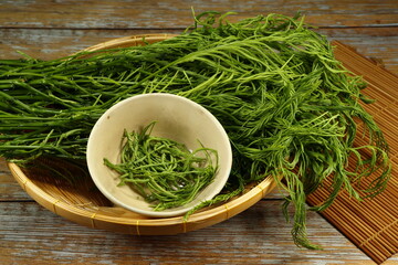 Pile of fresh and organic climbing wattle on the wooden basket. Famous ingredient in Asia restaurant. Mock up of product concept.