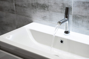 Modern bathroom faucet. Flowing water from water tap, copy space.