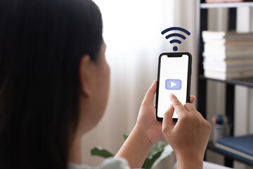 Woman using mobile phone connect to wifi for using online application. Woman use wifi to play multi-media application on phone. Finger touch phone screen with wifi icon.