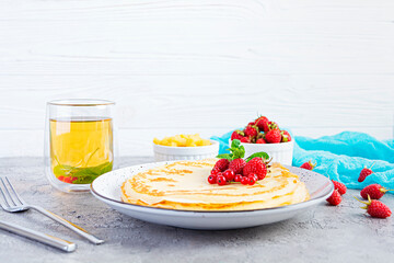 Pancakes with caramelized apples, raspberries, strawberries and red currants. Brunch with green tea and crepes.