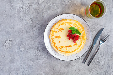 Pancakes with caramelized apples, raspberries, strawberries and red currants. Brunch with green tea and crepes.