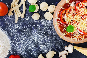 Raw pizza dough with ingredients and spices on dark background. Top view