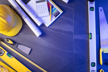Contractor theme. Plans,  notebook and tool kit of the contractor: yellow hardhat, libella, saw and...