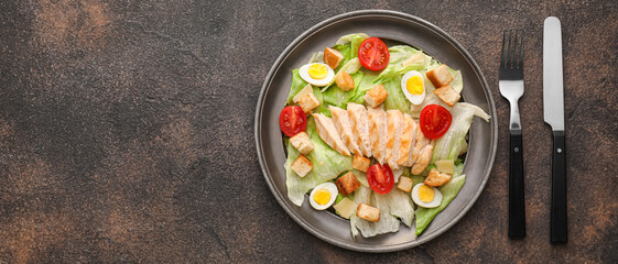 Plate with tasty Caesar salad on grunge background with space for text, top view