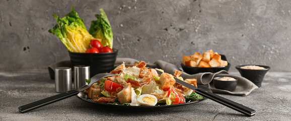 Plate with tasty Caesar salad on grey background