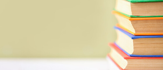 Stack of books on color background with space for text, closeup