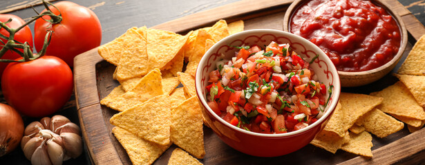 Bowls of tasty salsa sauces and nachos on table