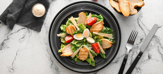 Plate with tasty Caesar salad on light background, top view