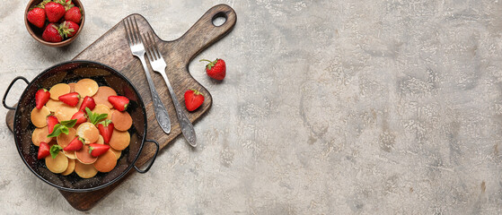 Composition with frying pan of mini pancakes and strawberry on grey background with space for text