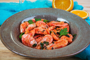 Fried shrimps with spicy orange sauce on wooden background