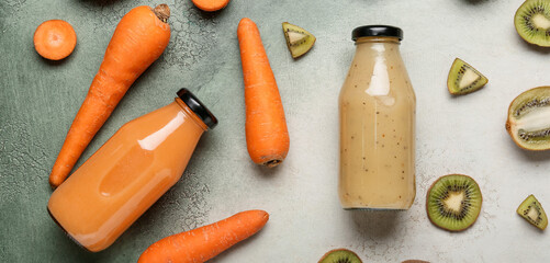 Bottles of healthy smoothies with carrot and kiwi on grunge background