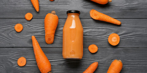 Bottle of healthy carrot smoothie on dark wooden background, top view