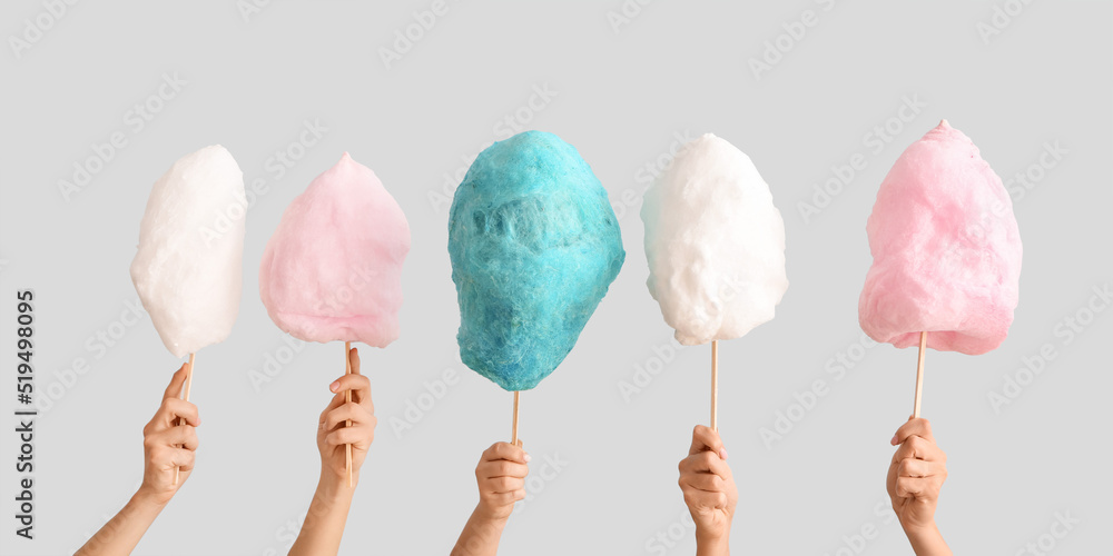 Wall mural Female hands with different cotton candy on light background