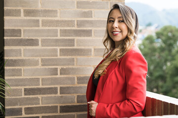 young saleswoman, elegantly dressed in a red jacket and smiling. Sense of security, wholeness and personal development. portrait of a beautiful Colombian woman. 