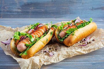 Homemade hot dog with sausage, salad, carrot, cucumber and tomato on wooden background
