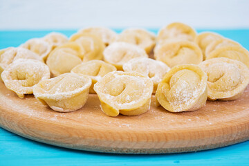 Homemade raw dumplings, pelmeni, on wooden background.