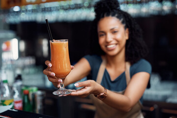 Close up of waitress holding glass of fresh fruit juice.