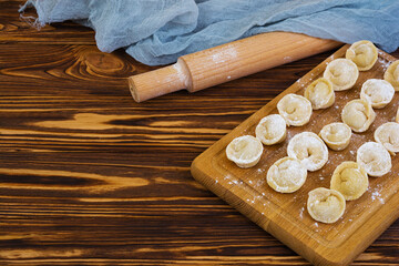 Homemade raw dumplings, pelmeni, on wooden background.