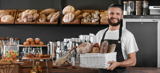 Male baker holding basket with fresh bread in market