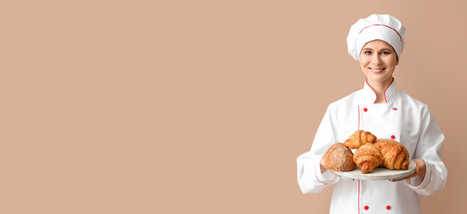 Female baker with fresh bakery on color background with space for text