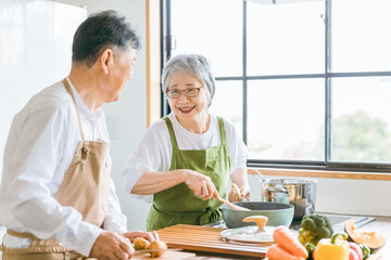 家で一緒に料理を作る笑顔の日本人老夫婦（高齢者）
