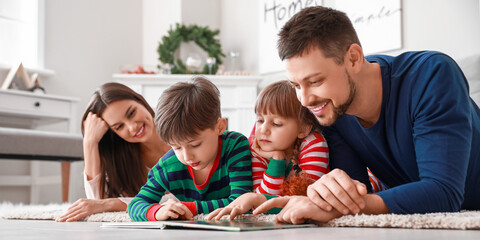 Happy family reading book at home on Christmas eve