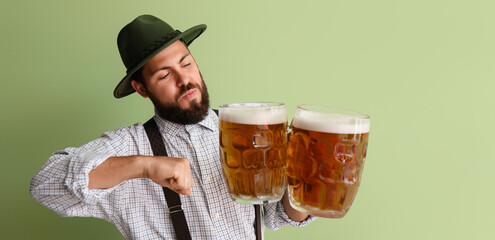 Man in traditional German clothes and with beer on green background. Octoberfest celebration