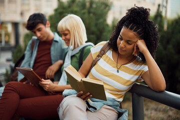 African American female student learning from book at campus.