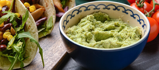 Bowl with tasty guacamole on table, closeup
