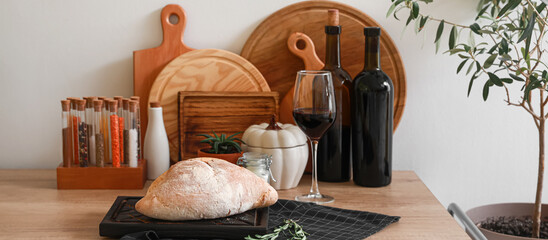 Fresh bread with red wine and kitchen utensils on table