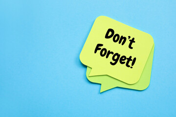 Heart shaped sticky note with text DON'T FORGET on blue background