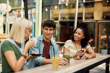 Group of young multiracial people communicating while relaxing in cafe.