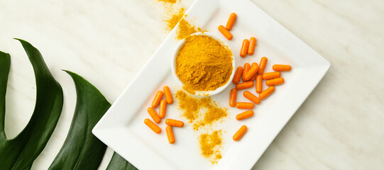Plate with turmeric pills and bowl with powder on light background