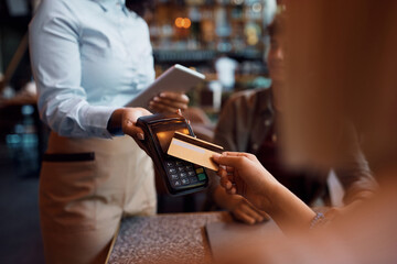 Close up of woman paying contactless with credit card in cafe.