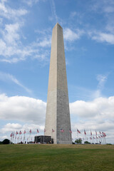 The Washington Monument, an obelisk-shaped building within the National Mall towering over Washington, DC, against a blue sky and clouds.