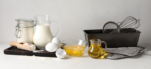 Ingredients for baking and kitchen utensils on light background