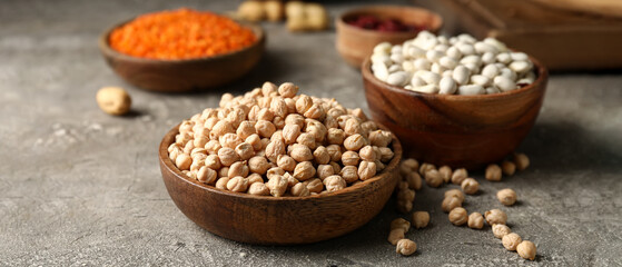 Wooden bowl with dried chickpea on grunge background
