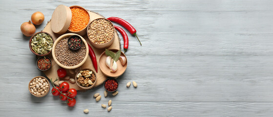 Fototapeta na wymiar Different raw legumes with spices and nuts on grey wooden background with space for text