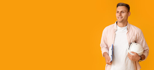 Young male architect with hardhat on yellow background with space for text