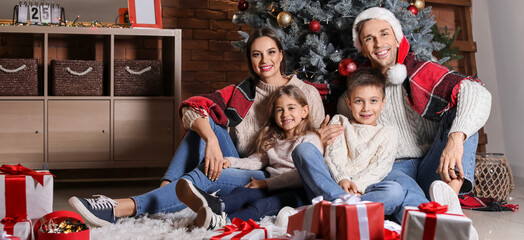 Happy family sitting under Christmas tree at home