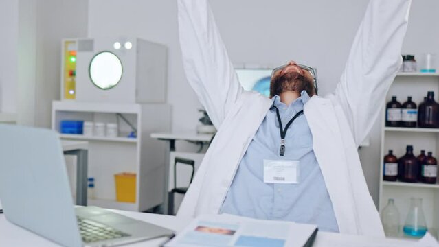 Cheerful, excited scientist celebrating his success after reading email about good news. Healthcare worker typing on laptop and feeling like a winner after making a medical breakthrough