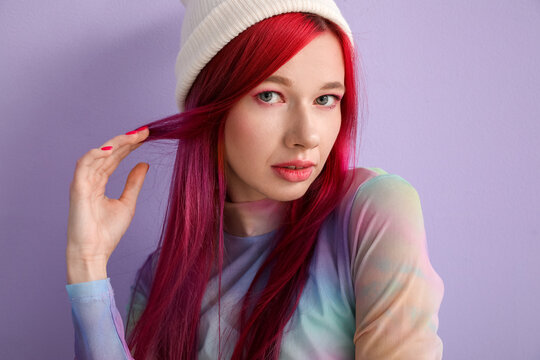 Beautiful young woman with bright hair on lilac background