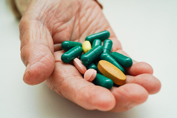 Asian elderly woman holding pill drug in hand, strong healthy medical concept.