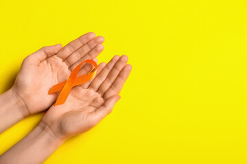 Woman with orange awareness ribbon on yellow background. Kidney cancer concept