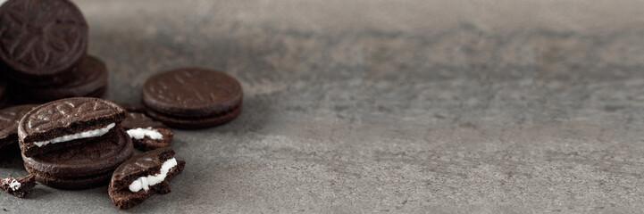 Chocolate cookies filled with cream on concrete background for banner. Copy space