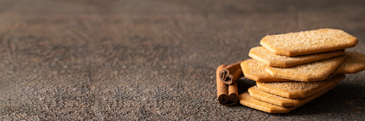 Rectangular cinnamon cookies with cinnamon sticks on concrete bakground for banner. Copy space