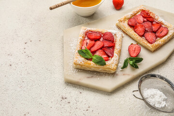 Board with sugar powdered puff pastry and strawberry on light table