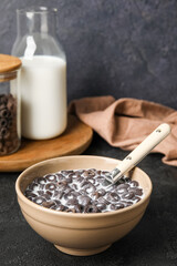 Bowl with tasty cereal rings and milk on dark background