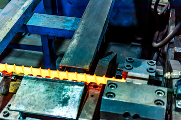 Obraz na płótnie Canvas Machine for induction heating of metal. A metal rod heated in an induction furnace. Hot metal processing. Metalworking in the industrial workshop at the factory.