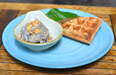 Homemade ice cream with waffle on a blue plate on wooden table